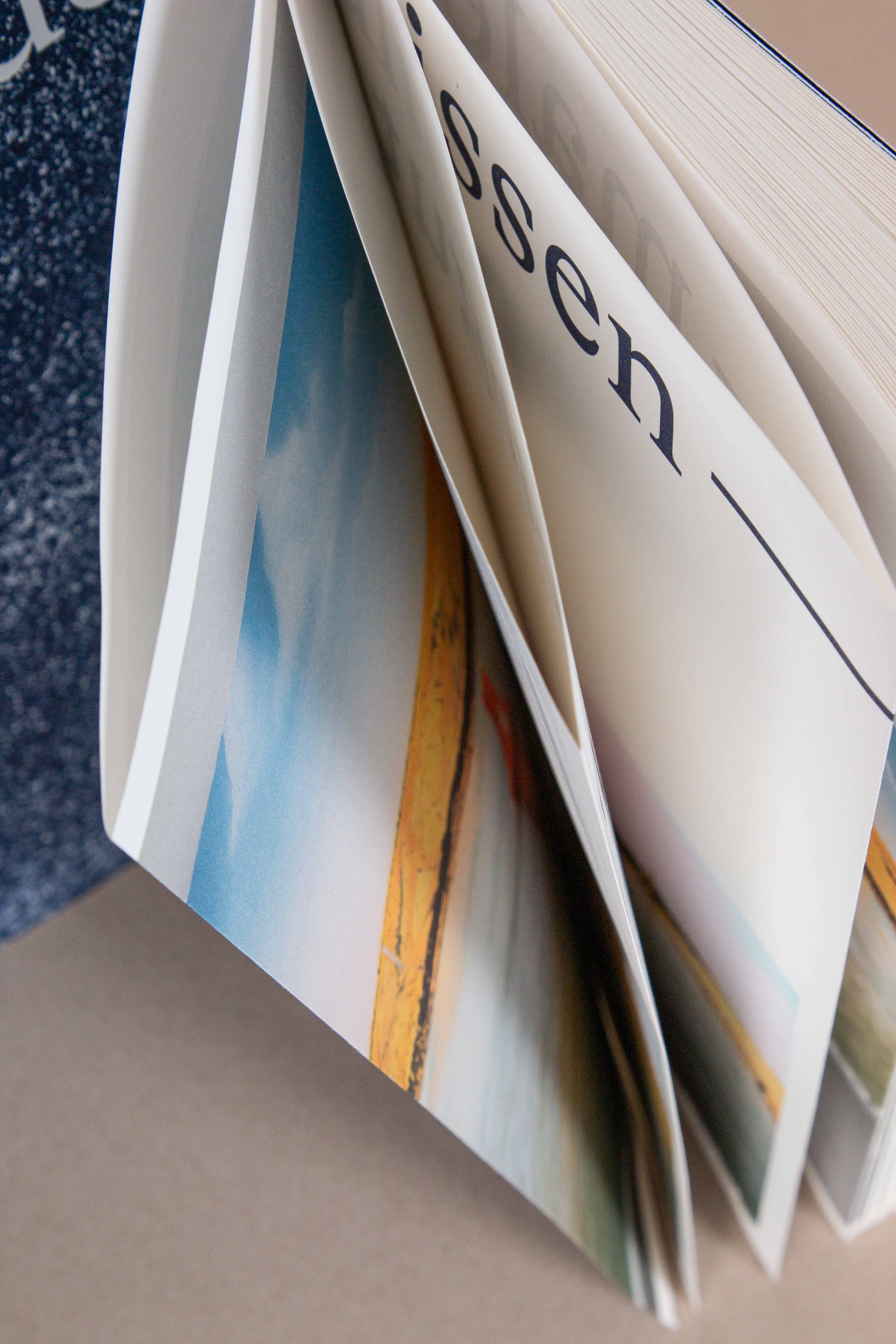 Close-up of partially turned magazine pages showing a mix of text and a landscape photo.